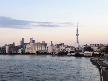 River and buildings against sky during sunset