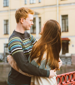 Couple embracing while standing against built structure