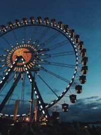 Low angle view of illuminated ferris wheel against sky at dusk