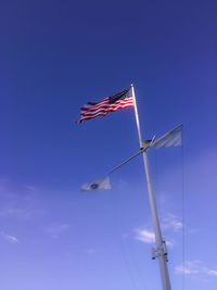 Low angle view of flag flying against blue sky