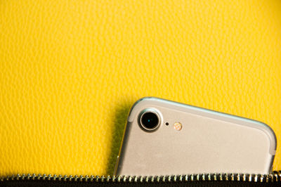 High angle view of smart phone against yellow background