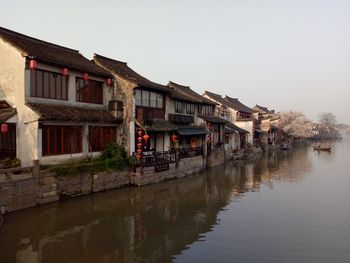 Houses by water against clear sky