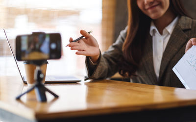 Midsection of woman using mobile phone at table