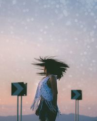 Young woman flying bird against sky