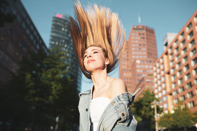 Woman with tousled hair against buildings in city