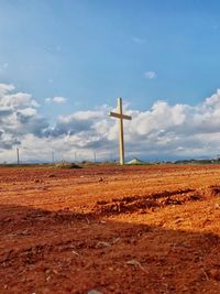 Cross on field against sky