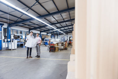 Two businessman standing in shop floor, discussing plans