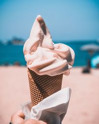 Midsection of woman holding ice cream against sea