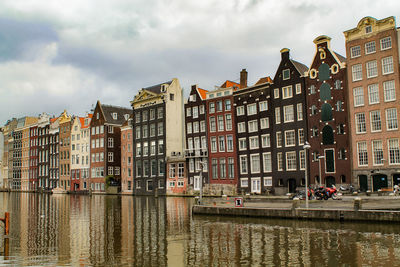 Buildings by canal against sky in city