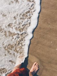 Low section of man standing on sand at beach