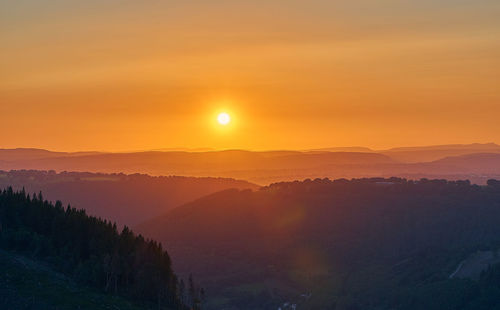 Scenic view of silhouette mountains against orange sky