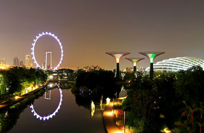 Illuminated ferris wheel against sky at night