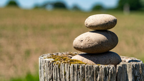 Closeup of three balancing stones on top of an old wooden post