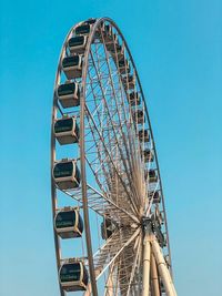 Low angle view of ferris wheel against clear blue sky