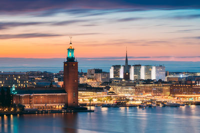 Illuminated buildings in city at sunset