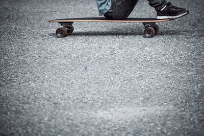 Low section of boy skateboarding on road