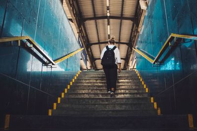 Rear view of woman walking on stairs at railway station