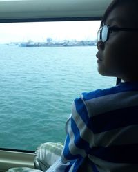 Side view of boy on boat in sea