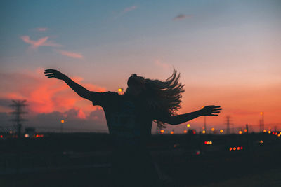 Silhouette woman with arms outstretched against sky during sunset