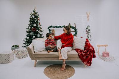 Cute young laughing family sitting at the sofa at home near the christmas tree