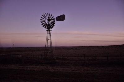 Windmill on field against sky at sunset