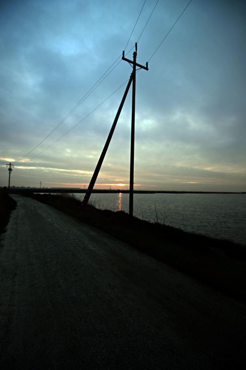 sky, cloud, nature, horizon, water, sunset, transportation, dusk, sea, cable, electricity, sunlight, light, technology, beauty in nature, power generation, environment, road, no people, line, evening, scenics - nature, land, tranquility, dramatic sky, darkness, silhouette, architecture, outdoors, power supply, landscape, tranquil scene, beach, power line, electricity pylon, street, reflection, built structure, city, wind, dark, the way forward