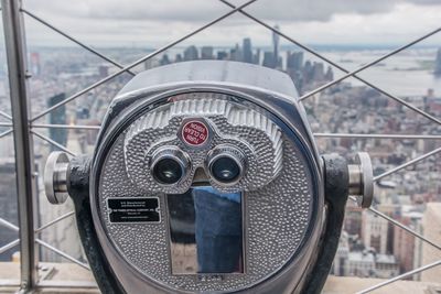 Close-up of coin-operated binoculars against cityscape