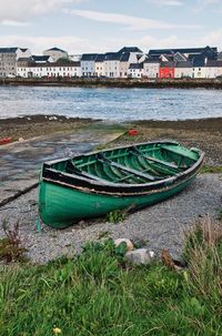 Fishing boats moored on beach against sky