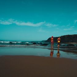 People standing on beach against sky