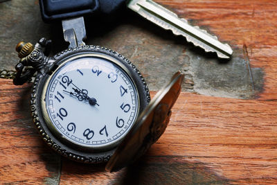 Close-up of pocket watch and keys on table