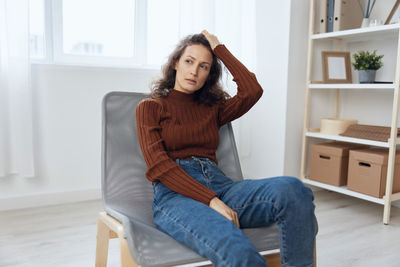 Depressed woman looking away sitting on chair
