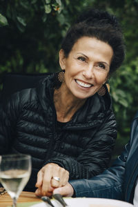 Smiling senior woman holding hands of man while sitting at dining table during garden party