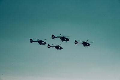 Silhouette of helicopters against clear sky