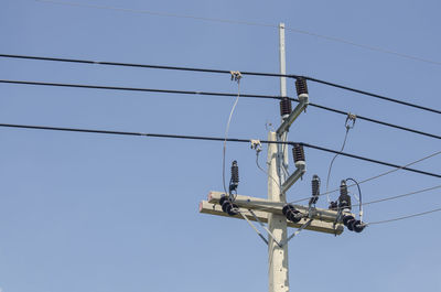 Low angle view of electricity pylon against clear sky