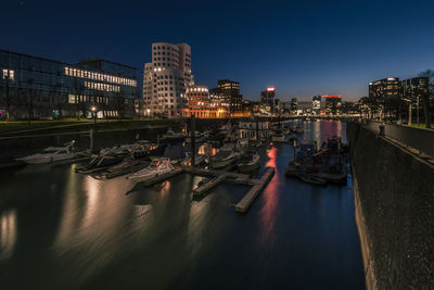 Sailboats moored on river in city at night