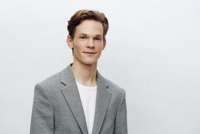 Portrait of young man standing against white background