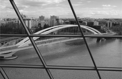 Bridge over river by buildings against sky