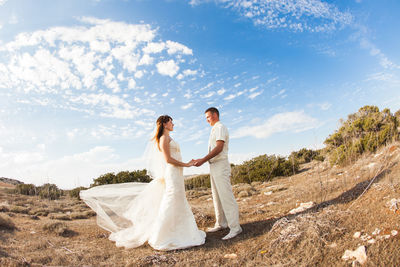Couple kissing in park against sky