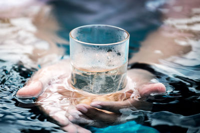 Close-up of hand drinking glass with water