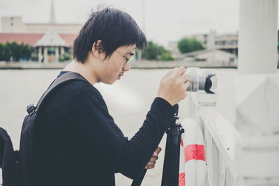 Side view of young man photographing with camera