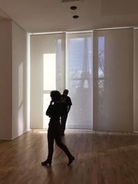 Full length of man and woman standing on hardwood floor at home