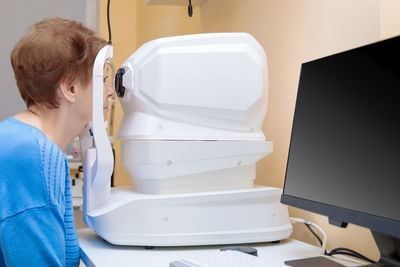 An adult woman at an ophthalmologist's appointment checks her vision on a special apparatus. 