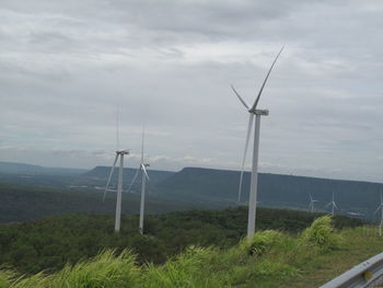 Wind turbines on field against sky