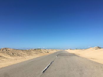 Sand dunes in desert against blue sky