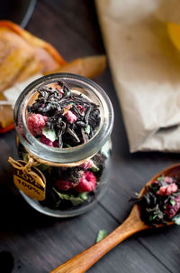 Dry tea with raspberry  in jar and spoon on dark wooden table