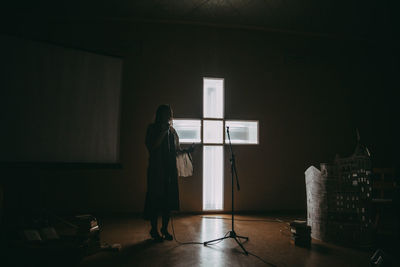 Rear view of woman looking through window at home