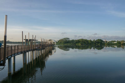 Wooden posts on river against sky