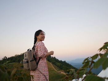 Side view of woman standing on mountain against sky