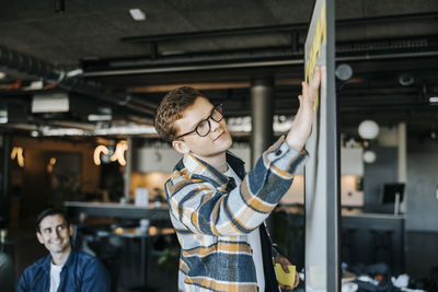 Businessman sticking adhesive notes on whiteboard in office