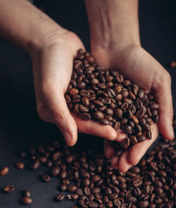 Cropped hands of woman holding roasted coffee beans